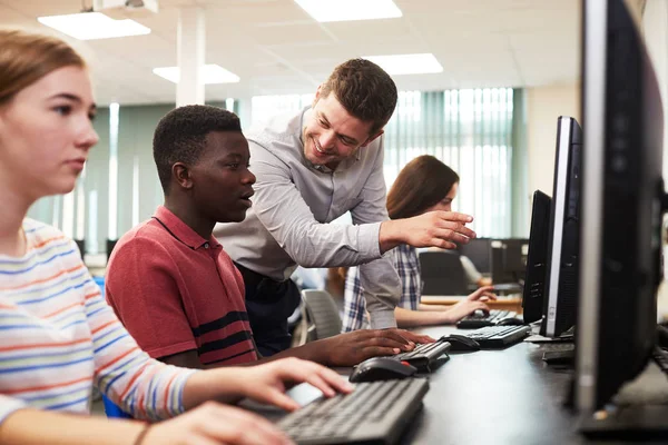 教师帮助男中学生在计算机课堂上工作 — 图库照片