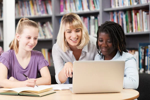 Nauczyciel Pomaga Dwa Kobieta Licealistów Działa Laptopie Bibliotece — Zdjęcie stockowe