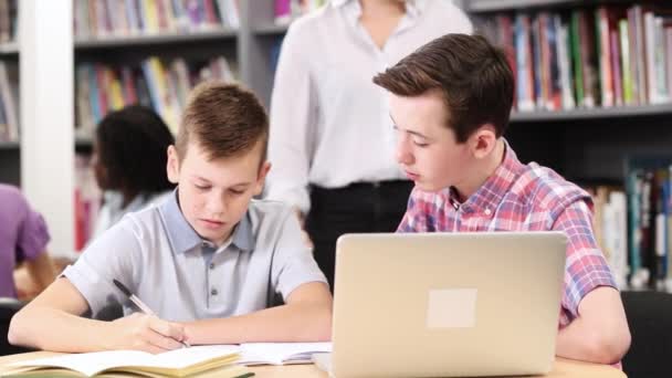 Lehrerin Hilft Zwei Männlichen Gymnasiasten Beim Arbeiten Laptop Der Bibliothek — Stockvideo