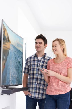 Genç çift evde yeni kavisli ekran televizyonlu