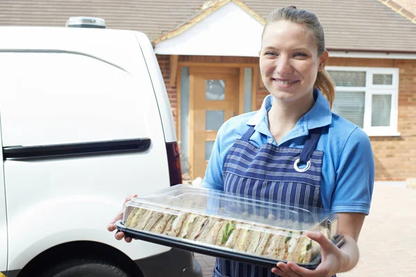 Female Caterer Delivering Tray Of Sandwiches To House