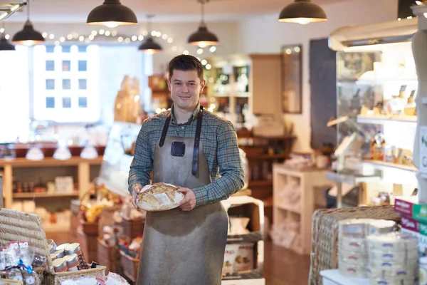 Portrait Smiling Male Owner Delicatessen Shop Wearing Apron Holding Loaf — Stock Photo, Image