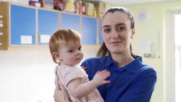 Porträt Einer Kindergärtnerin Die Ein Junges Mädchen Einer Kindertagesstätte Hält — Stockvideo