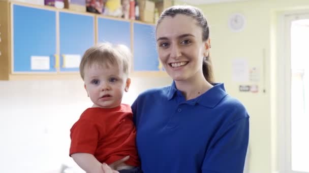 Portrait Female Nursery Worker Holding Young Boy Childcare Centre — Stock Video