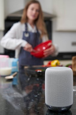 Evde Yemek Hazırlayan Kadın Dijital Asistan Sorusu Soruyor  
