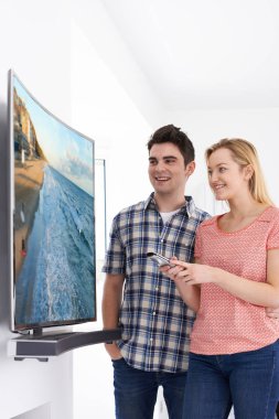 Genç çift evde yeni kavisli ekran televizyonlu