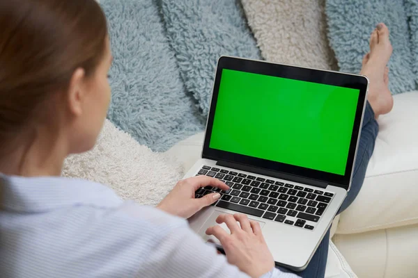 Over de schouder weergave van de vrouw liggend op de Bank met behulp van groen scherm — Stockfoto