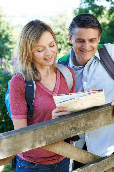 Mature Couple Hiking In Countryside Looking At Map