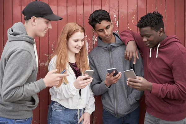 Gruppe Jugendlicher schaut in städtischen Siedlungen auf Mobiltelefone — Stockfoto