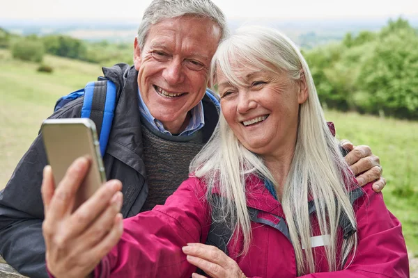 Sorridente anziano coppia escursionismo in campagna in piedi da cancello un — Foto Stock