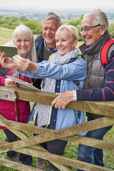 Group Of Senior Friends Hiking In Countryside Standing By Gate — Stock Photo, Image