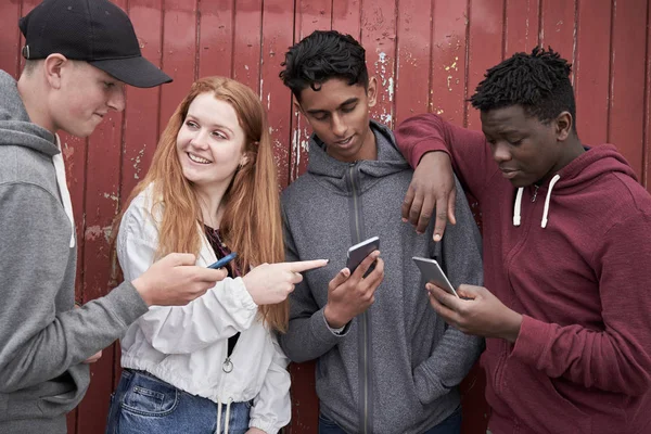 Группа друзей-подростков, рассматривающих мобильные телефоны в городских условиях — стоковое фото