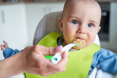 Evde gülümseyen erkek bebeğin portresi mama sandalyede besleniyor Sol