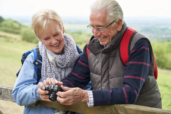 Senior para turystyka w Countryside stojący przez brama i biorąc — Zdjęcie stockowe