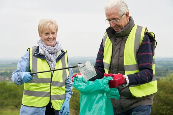 Hilfreiches Seniorenpaar sammelt Müll auf dem Land — Stockfoto