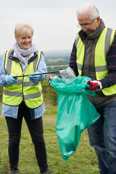 Helpful Senior Couple Collecting Litter In Countryside — Stock Photo, Image
