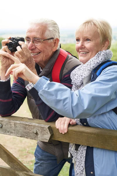 Senior paar wandelen in het platteland staan door de poort en het nemen van — Stockfoto