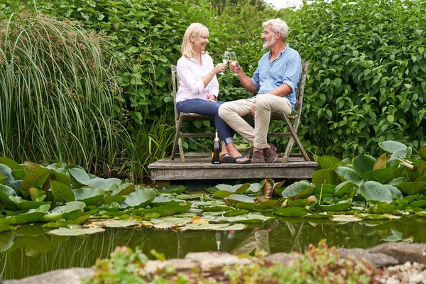 Äldre par firar med champagne sitter på stolar på W — Stockfoto