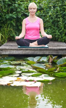 Lak tarafından Ahşap İskele Üzerinde Yoga Pozisyonunda Olgun Kadın Portresi