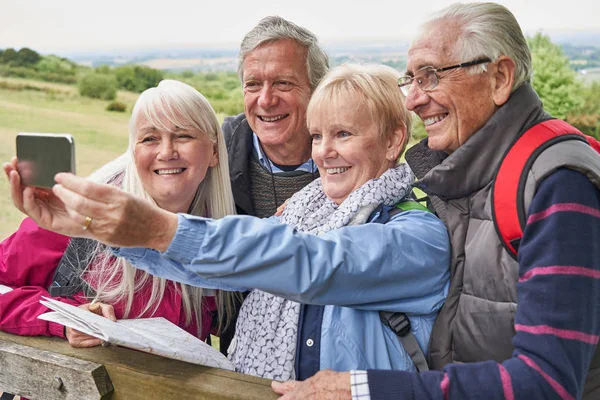Gruppe av eldre venner på fottur i landet stående ved porten – stockfoto