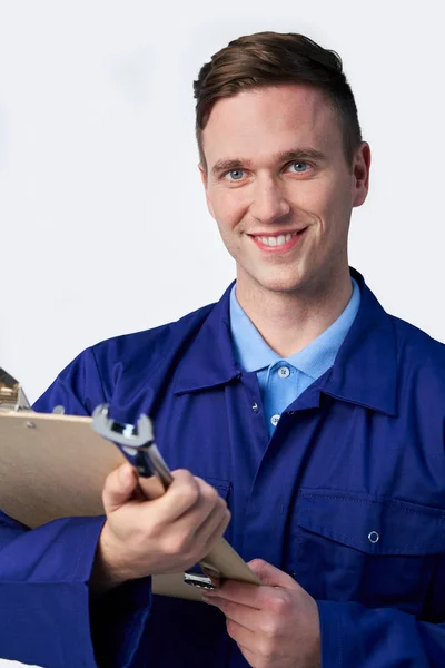 Studioporträt eines männlichen Ingenieurs mit Klemmbrett und Spannschlüssel agai — Stockfoto