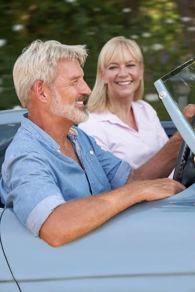 Зрелая пара наслаждается поездкой на классическом спортивном автомобиле — стоковое фото