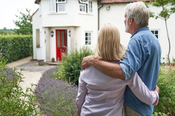 Rückansicht eines reifen Paares, das im Garten steht, Blick auf sein Traumhaus — Stockfoto