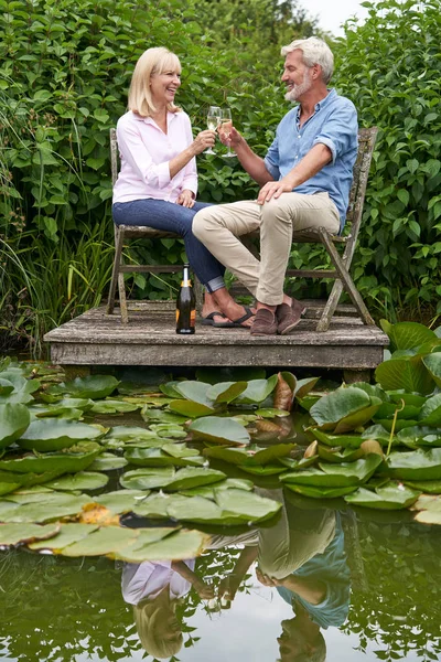 Ältere Paare feiern mit Champagner sitzend auf Stühlen auf w — Stockfoto