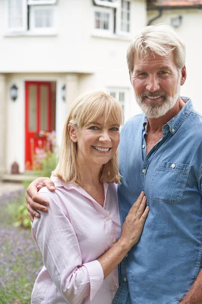 Porträt eines reiferen Paares, das im Garten vor Traumhaus steht — Stockfoto