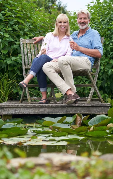 Porträt eines reifen Paares, das mit Champagner im Sitzen feiert — Stockfoto