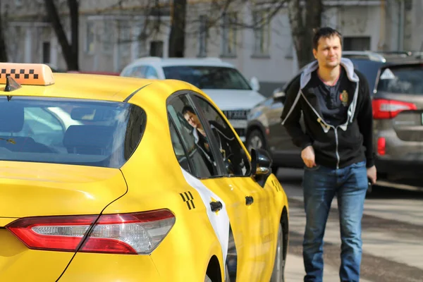 Egy homályos sziluett egy fiatal fickóról, aki egy sárga taxi felé sétál.. — Stock Fotó