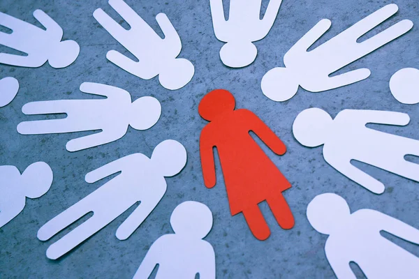 Rode papieren figuur van vrouw tegen silhouetten van mannen. Symbool van vrouwelijke leider. — Stockfoto