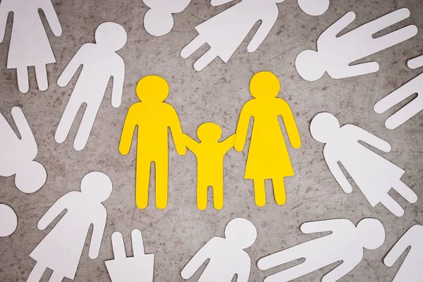 Papierowe figury rodziny są żółte. Białe sylwetki samotnych ludzi wokół. — Zdjęcie stockowe