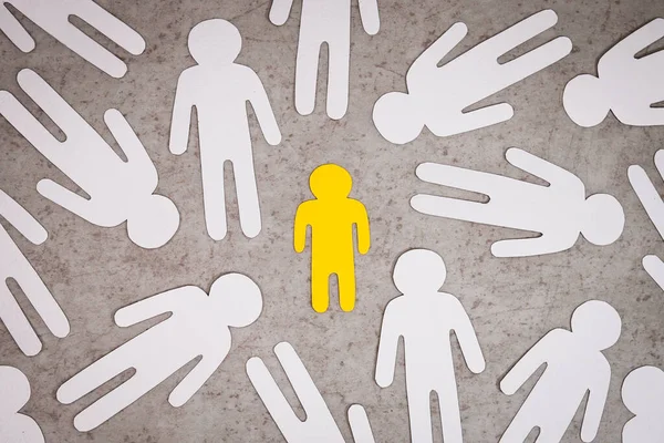 Figura amarilla de un niño se perdió entre las siluetas blancas de las personas. — Foto de Stock