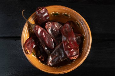 Meksika biberleri, kilden bir kasede, siyah arka planda.