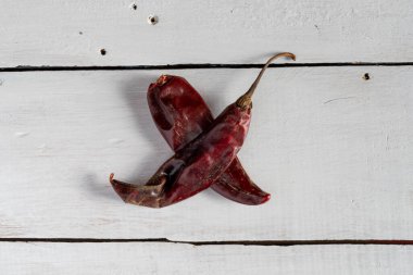 Beyaz ahşap arka planda iki kurutulmuş kırmızı biber.