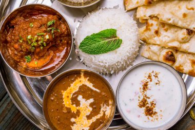 Ahşap arka planda çeşitli Hint yemekleri. Gerçekten de yemek, pirinç, mercimek, paneer, samosa, baharat, masala. Hint yemekli kase ve tabaklar.