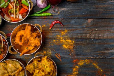 Ahşap arka planda çeşitli Hint yemekleri. Gerçekten de yemek, pirinç, mercimek, paneer, samosa, baharat, masala. Hint yemekli kase ve tabaklar.