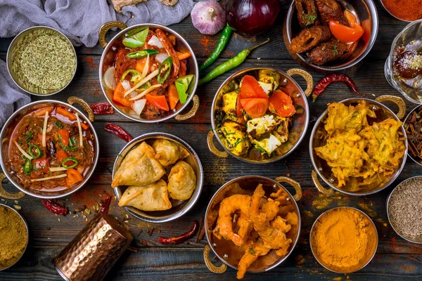 Ahşap arka planda çeşitli Hint yemekleri. Gerçekten de yemek, pirinç, mercimek, paneer, samosa, baharat, masala. Hint yemekli kase ve tabaklar.