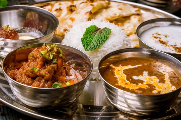 Ahşap arka planda çeşitli Hint yemekleri. Gerçekten de yemek, pirinç, mercimek, paneer, samosa, baharat, masala. Hint yemekli kase ve tabaklar.