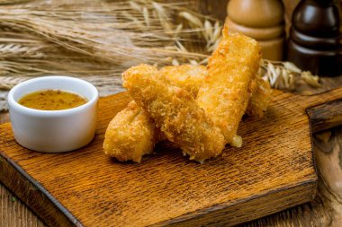 Tabağında sos olan kızarmış peynir çubukları.