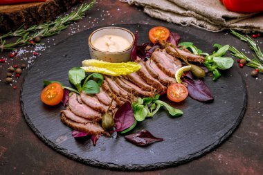 Koyu tabakta salata yapraklarıyla dilimlenmiş biftek. 