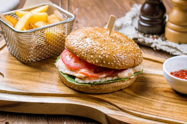 Burger with chicken with French fries on wooden plate