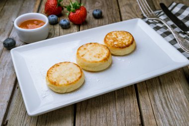 Süzme peynirden peynirli kekler ahşap masada.