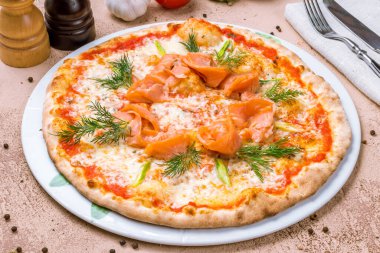 Beyaz tabakta deniz mahsullü İtalyan pizzası.