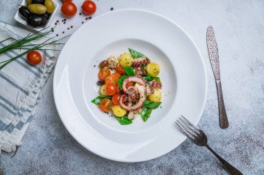 Sebzeli salata ve beyaz tabakta ahtapot.