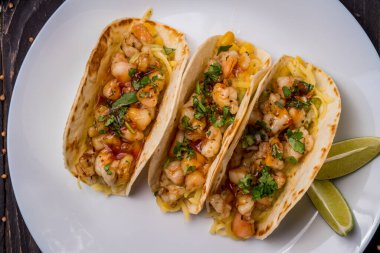 Beyaz tabakta Meksika karidesli taco.