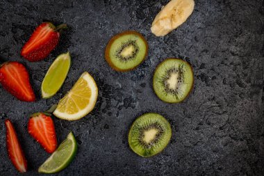 Kesilmiş meyve ve siyah beton arka plan.