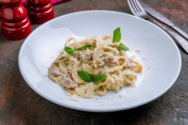 Beyaz tabakta domuz pastırmalı spagetti.