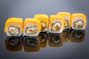 Erimiş peynirli suşi rulosu, siyah üzerine yansımalı.